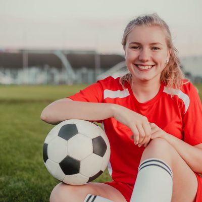 portrait-of-smiling-girl-football-player-with-soccer-ball-sitting-on-the-grass.jpg